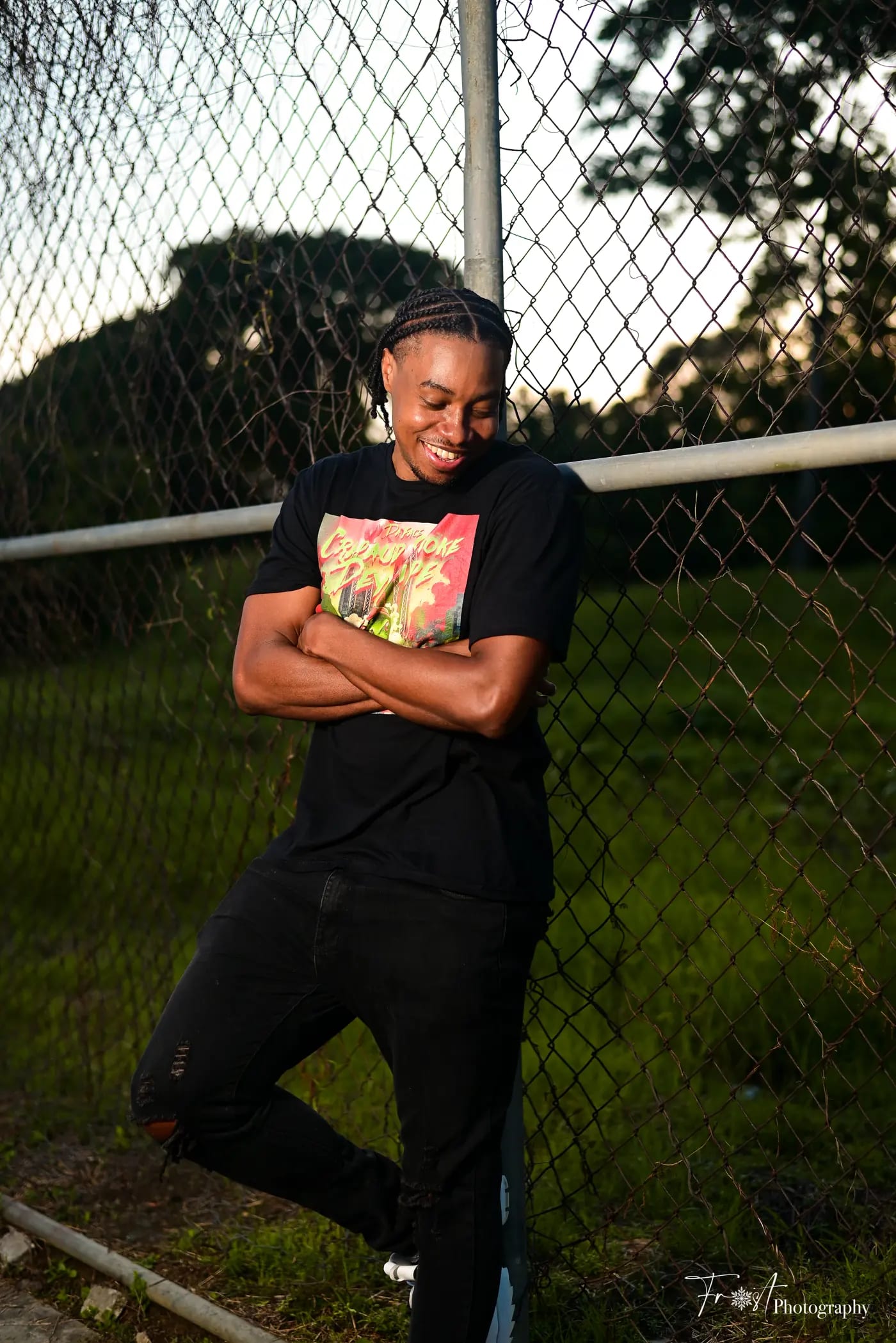 Portrait of the producer leaning against a chain-link fence.